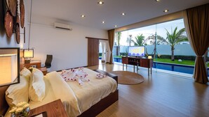 Un dormitorio con una cama grande, un escritorio, una silla y vista a una piscina.