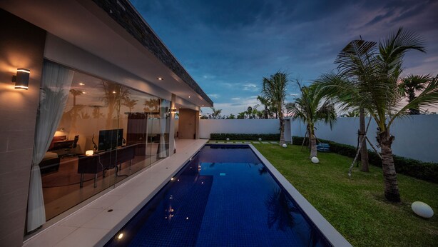 Una casa moderna con piscina, puertas de vidrio y un césped bien cuidado.