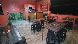 A cozy restaurant with wooden tables and chairs, a counter with a menu, and a wall decorated with cacti and a sun design. - Pamujo Hostel (Baclayon)
