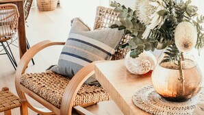 A dining area with a wooden table, wicker chairs, and a woven bench.