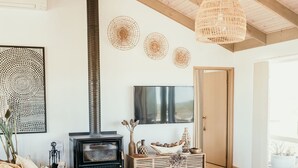 A modern living room with a large wooden table, leather sofas, a fireplace, and a TV mounted on the wall.