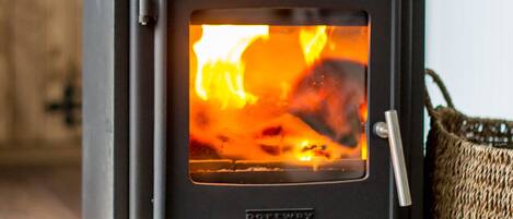 A wood-burning stove with visible flames, a metal handle, and a brand name "Porthway" on the front.