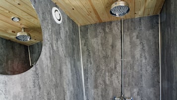 A shower area with a wooden ceiling and a concrete wall.