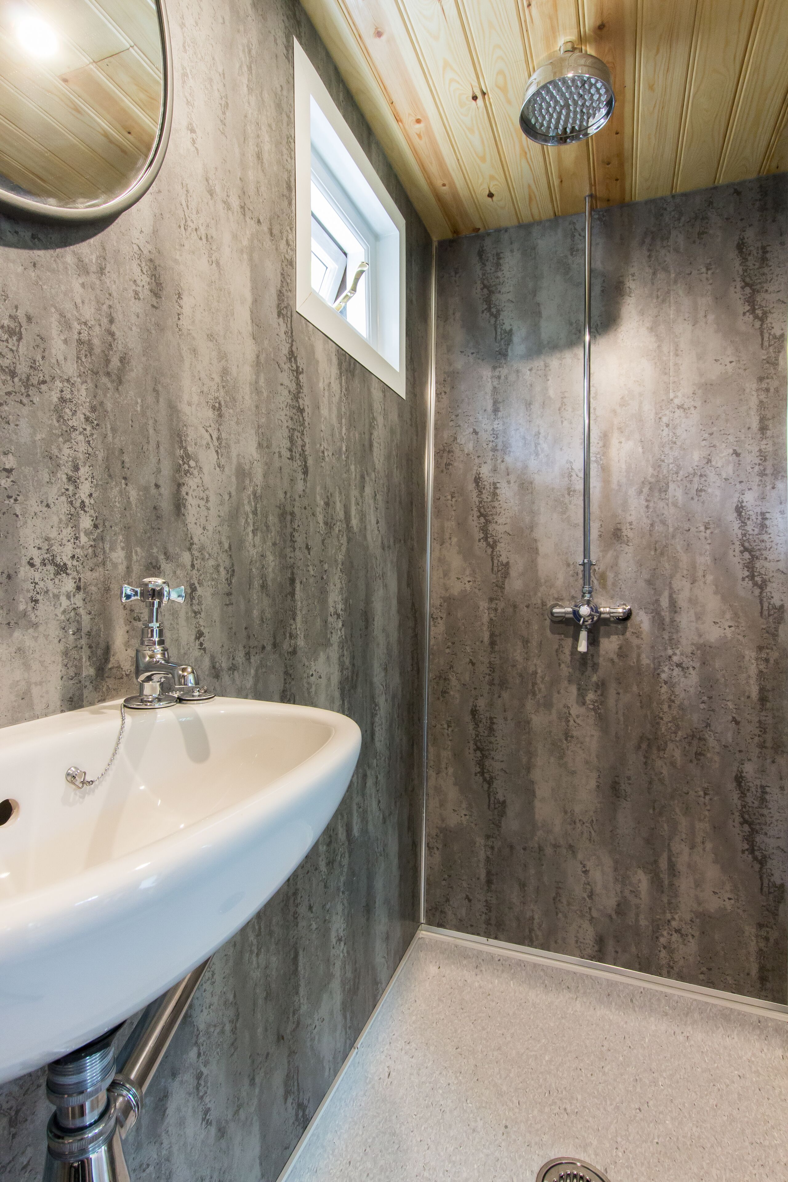 A bathroom with a white sink, a showerhead, and a window.
