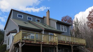 A two-story house with a covered deck and a garage. - Franconia Notch Retreat, Huge Views, Hot Tub, EV charger, A/C (Sugar Hill)