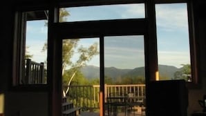 A room with large windows offering a view of a deck and mountains. - Franconia Notch Retreat, Huge Views, Hot Tub, EV charger, A/C (Sugar Hill)
