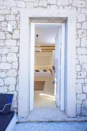 A narrow doorway leading into a room with a bed, a hanging light fixture, and a textured wall. - Sante Alacati (Cesme)