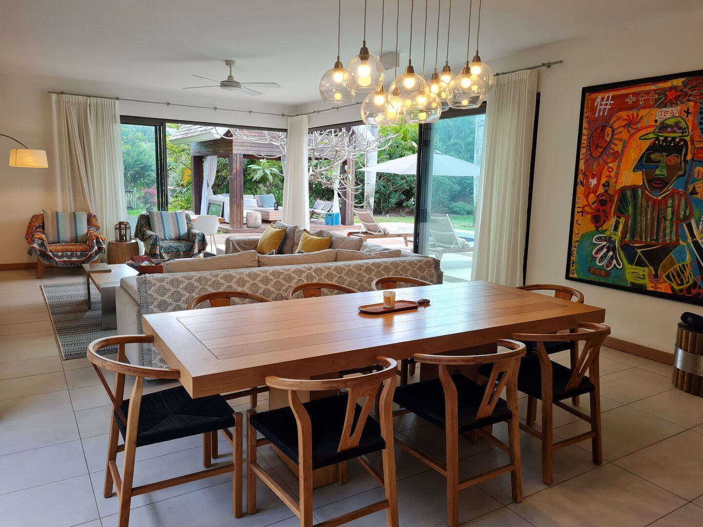 A spacious living area with a large wooden dining table, comfortable seating, and a view of the outdoors.