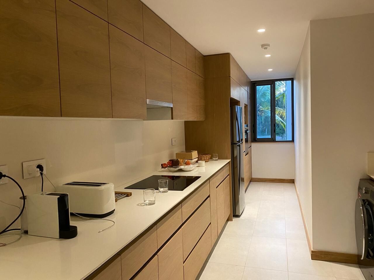 Una cocina moderna con armarios de madera, horno empotrado, refrigerador y ventana que proporciona luz natural.