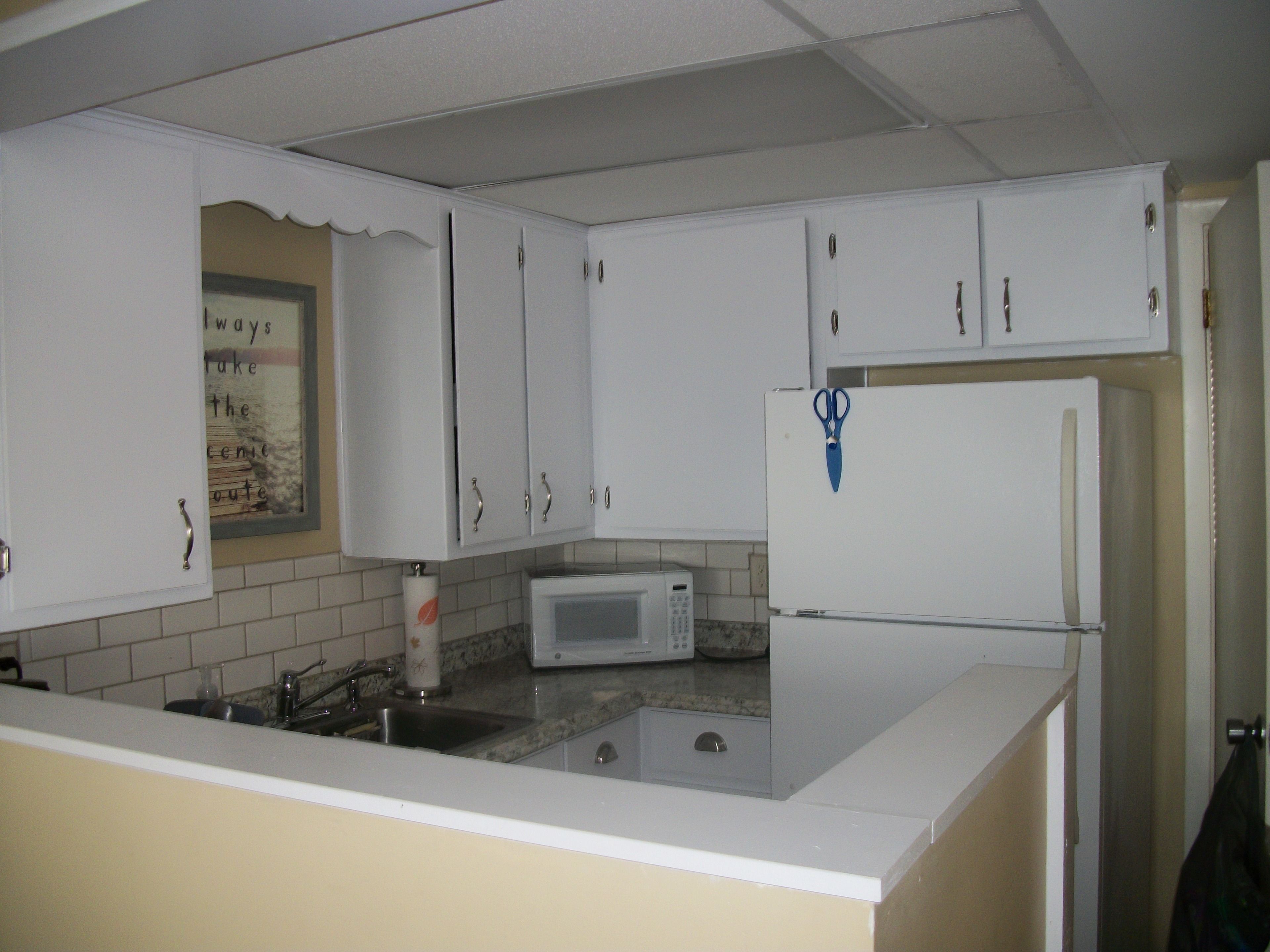 A kitchen with white cabinets, a microwave, and a refrigerator.
