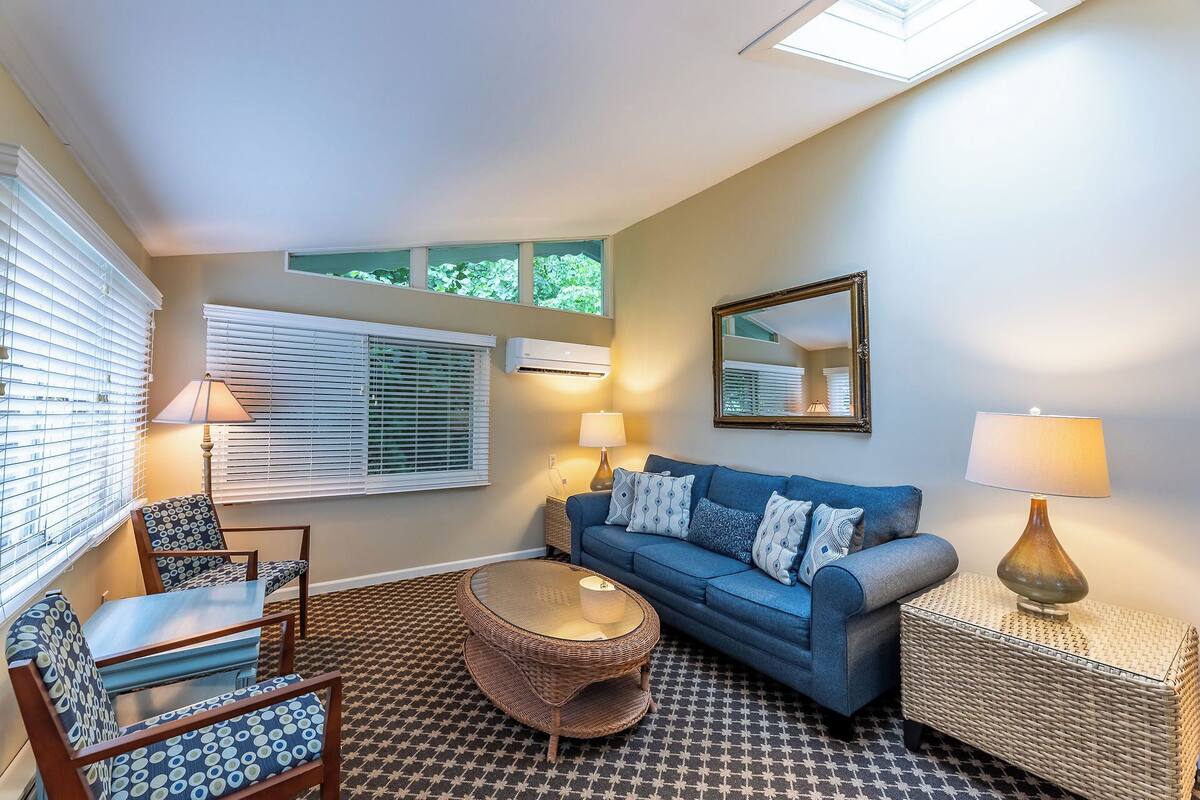 A living room with a blue sofa, two lamps, a mirror, and a patterned floor.