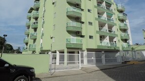 Un edificio de varios pisos con balcones, entrada protegida por una reja y cielo despejado.