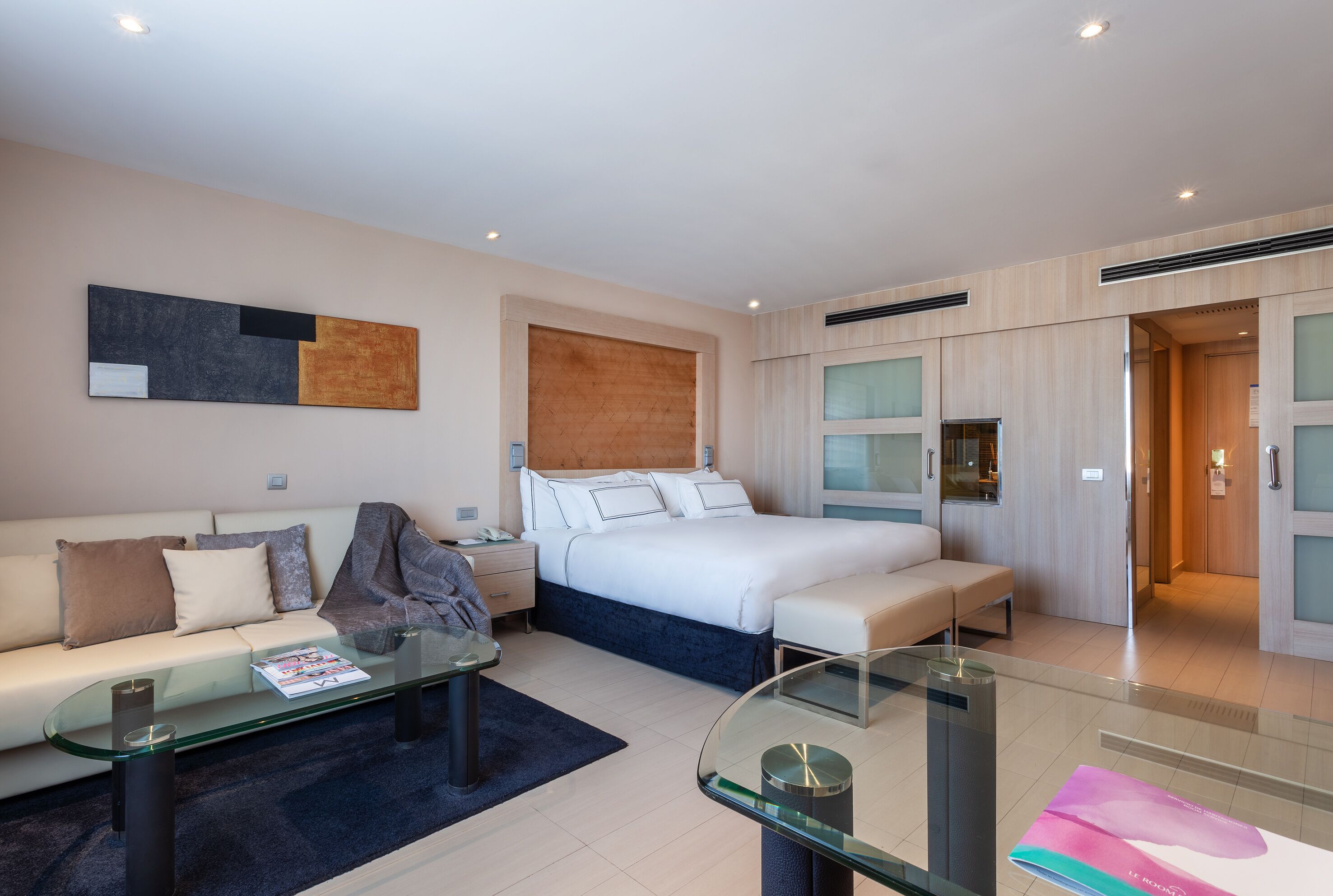 Une chambre d’hôtel moderne équipée d’un lit, d’un canapé, d’une table basse en verre et d’un bureau.