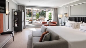 Une chambre d’hôtel moderne dotée d’un grand lit, d’un canapé, d’un bureau et d’un balcon aménagé avec du mobilier d’extérieur.