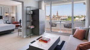 Une chambre d’hôtel comprenant un lit, un canapé, une table basse, une bibliothèque et un balcon avec vue sur la ville.