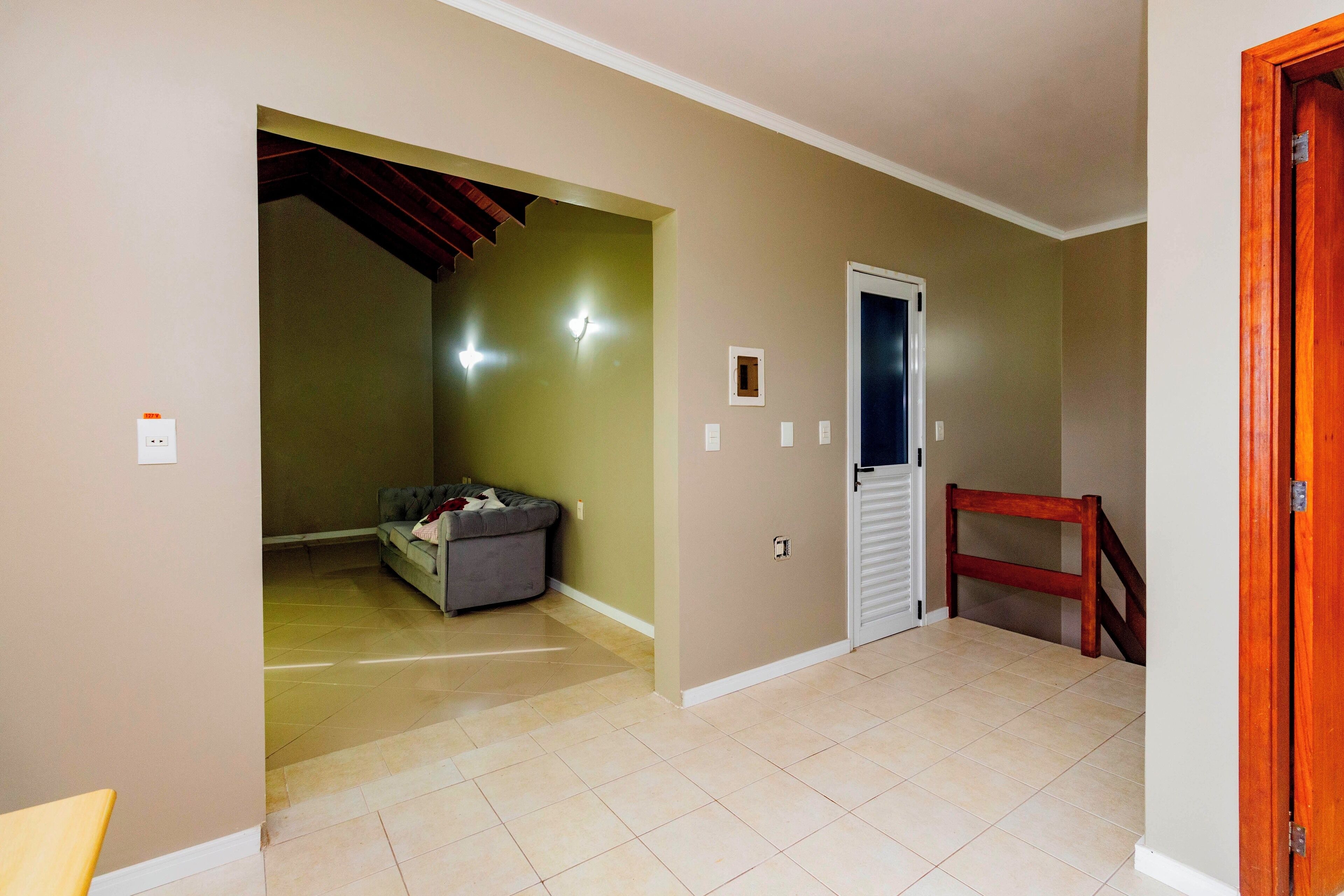 A hallway with a tiled floor, a door, and a staircase.