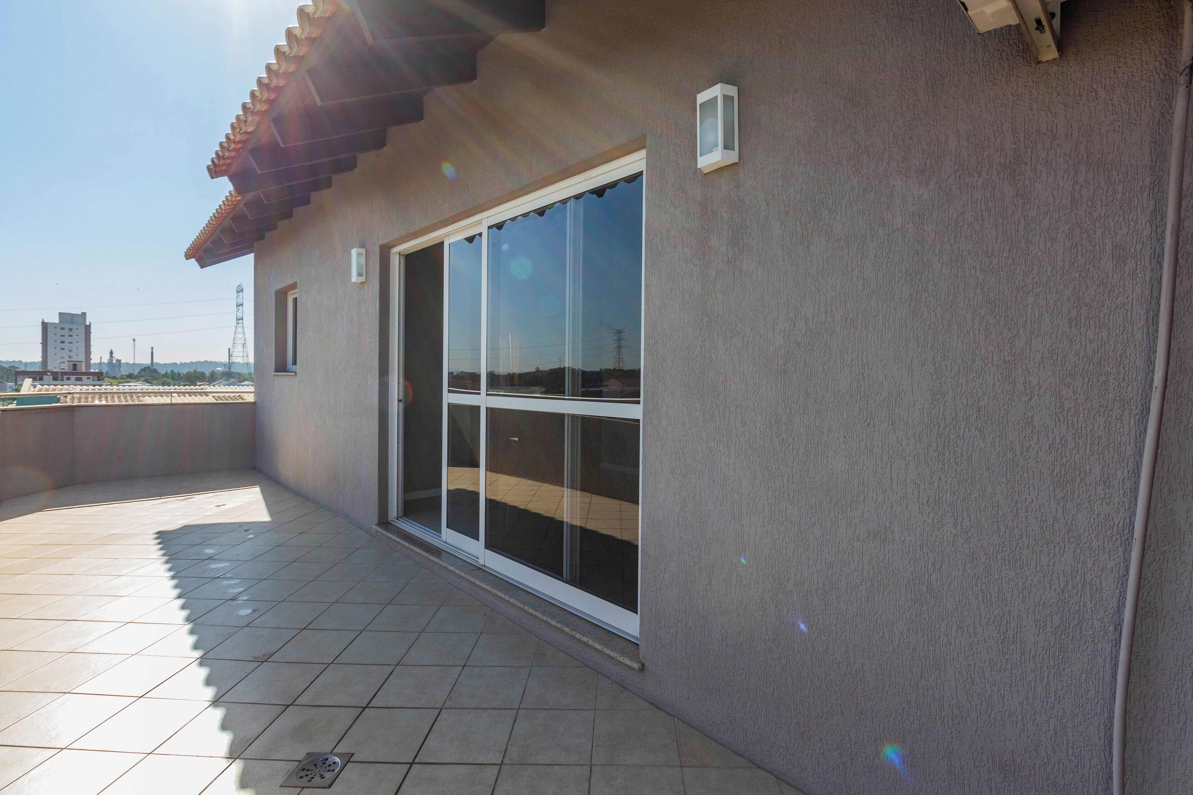 A balcony with a tiled floor and a sliding glass door.