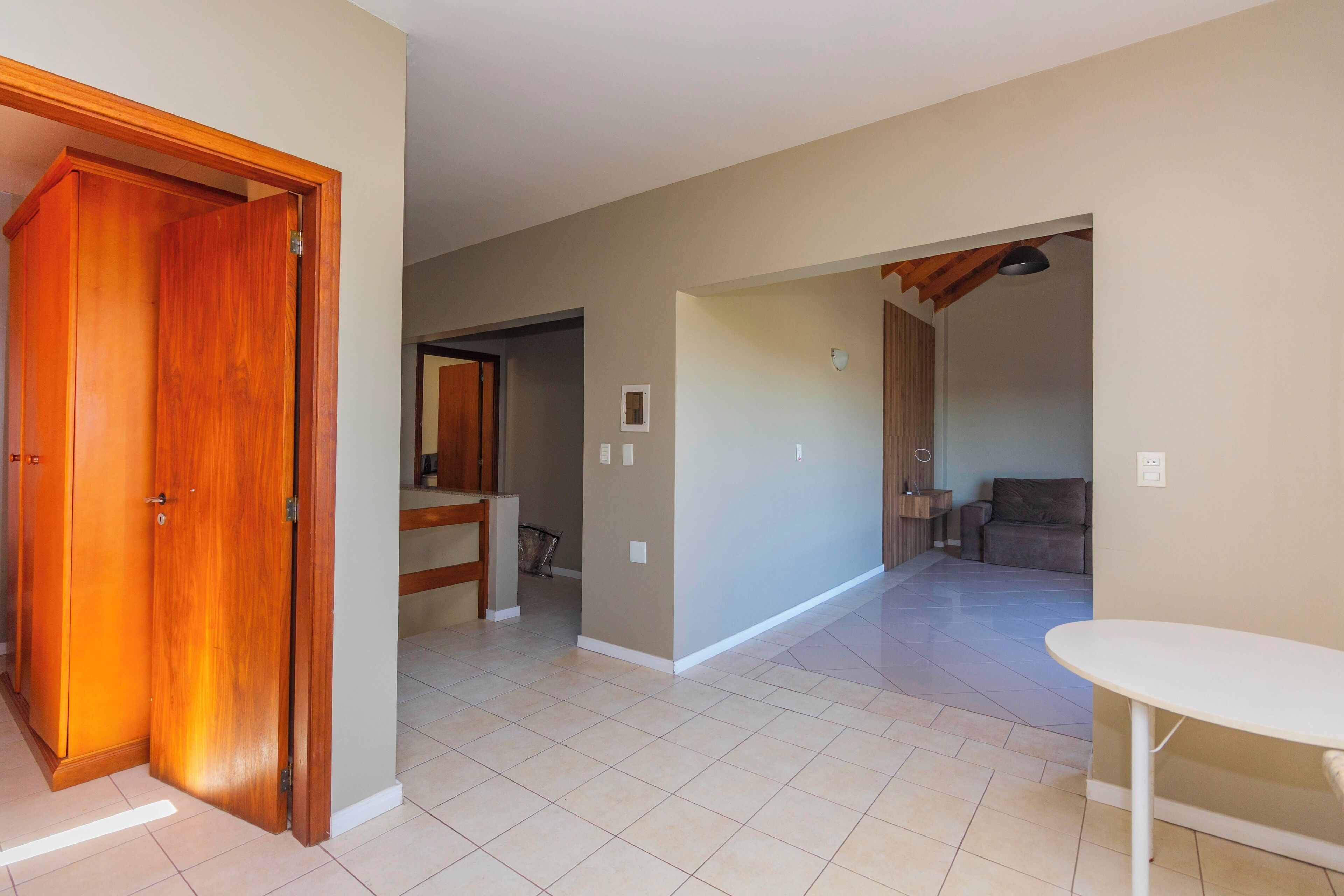 A spacious hallway with a wooden door, a white table, and a sofa in the background.