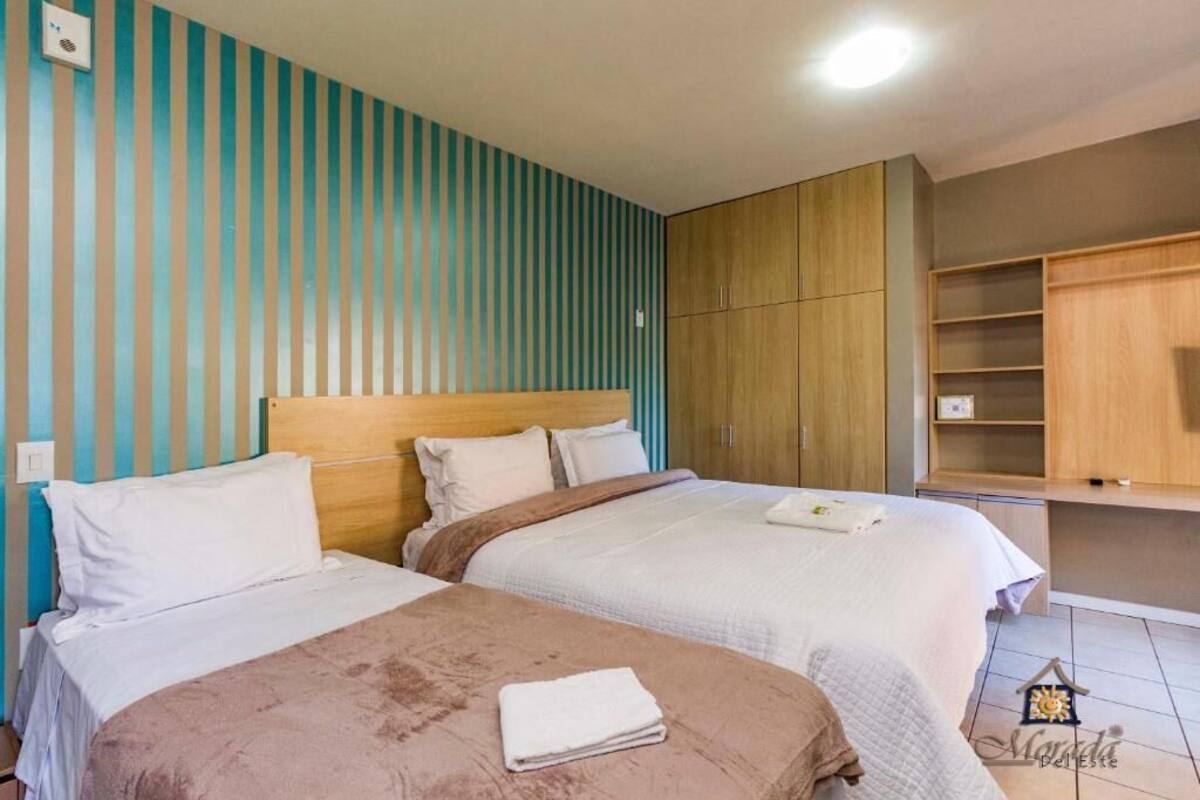 A hotel room with two beds, wooden headboards, and a built-in wardrobe.