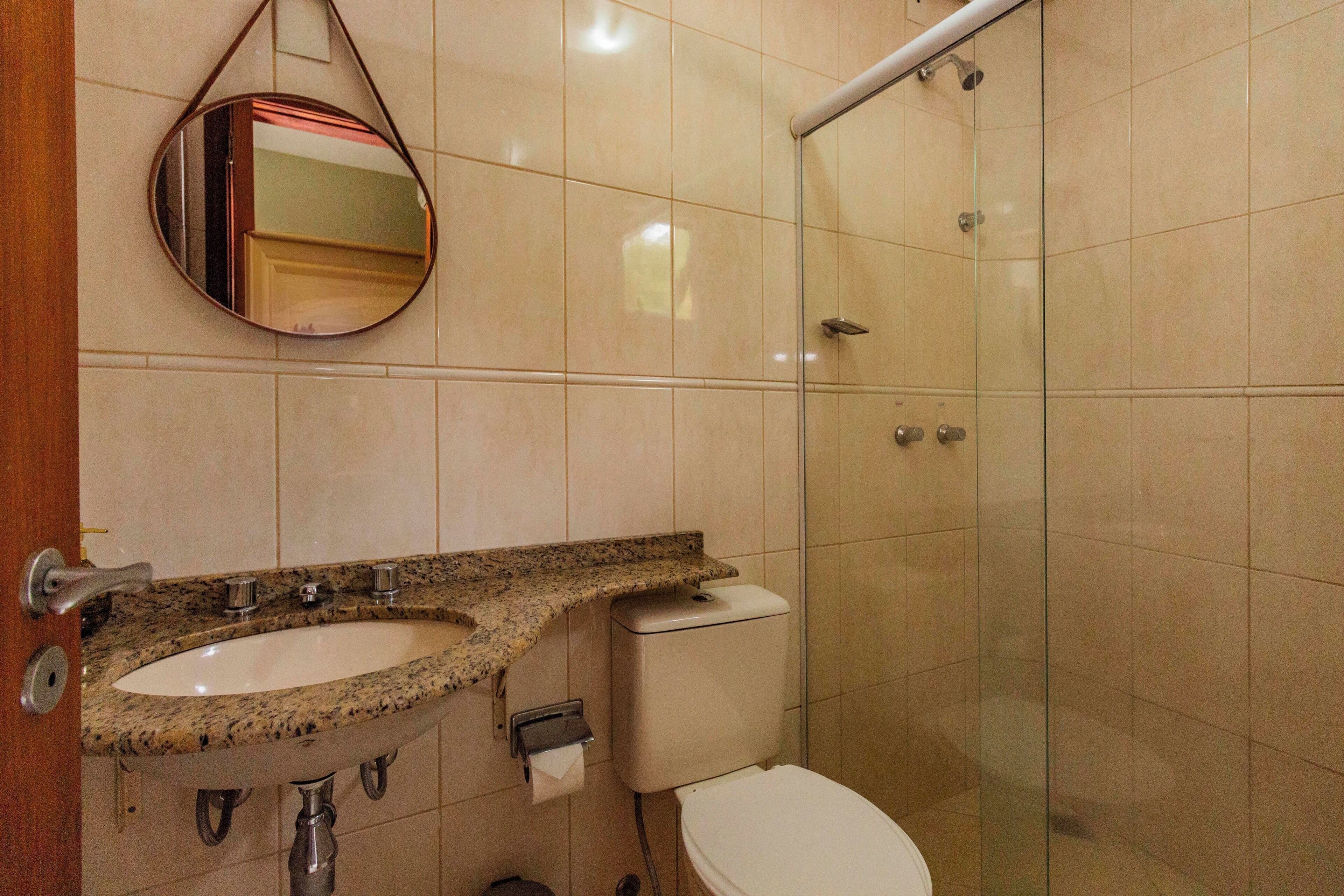 Un baño con lavamanos de encimera de granito, inodoro y cabina de ducha de vidrio.