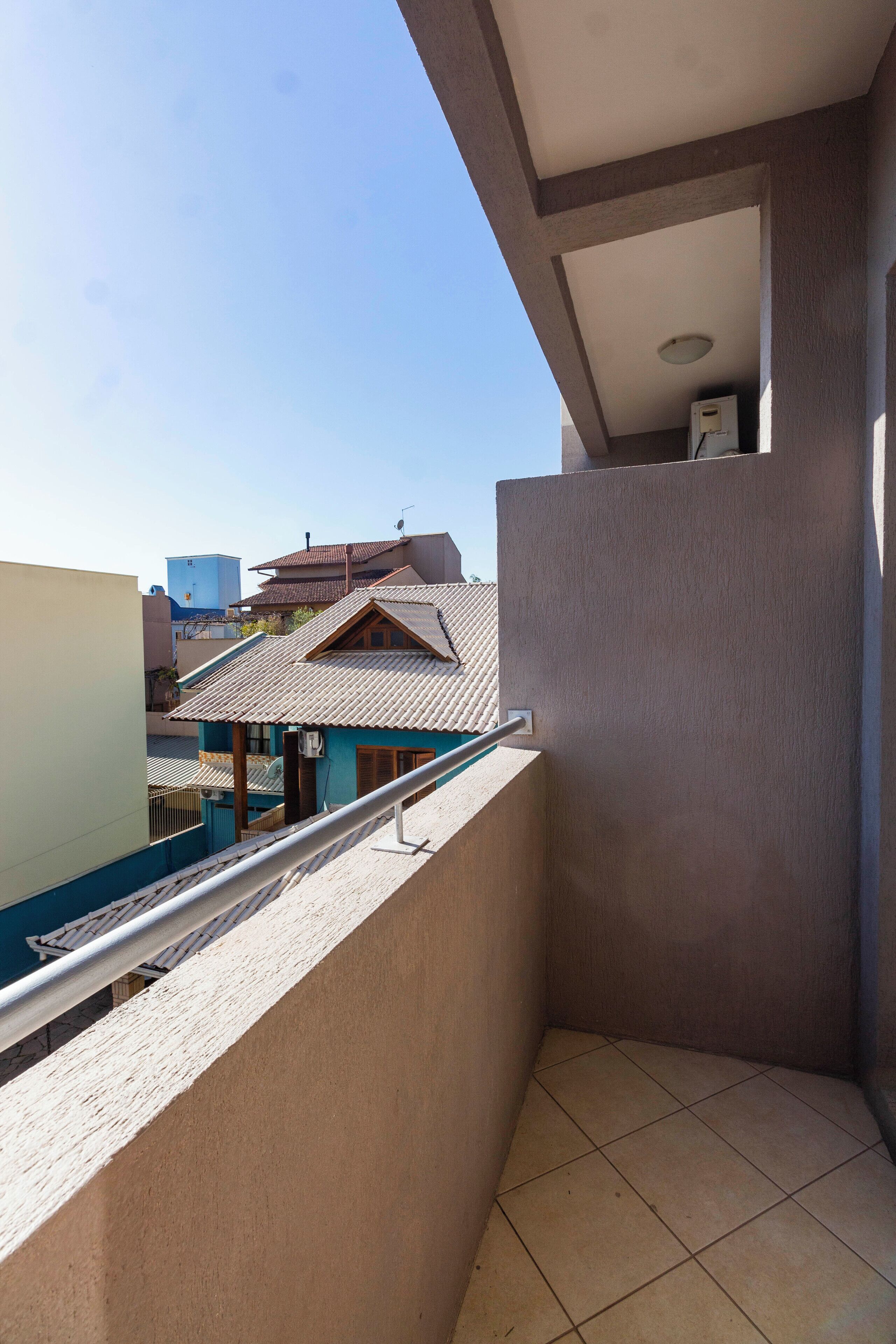A balcony with a view of neighboring buildings and a clear sky.