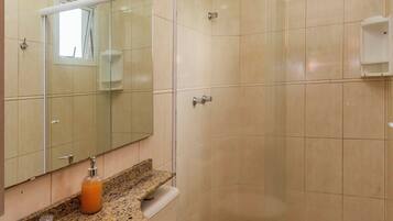 A bathroom with a granite countertop sink, a toilet, a glass shower enclosure, and a mirror.