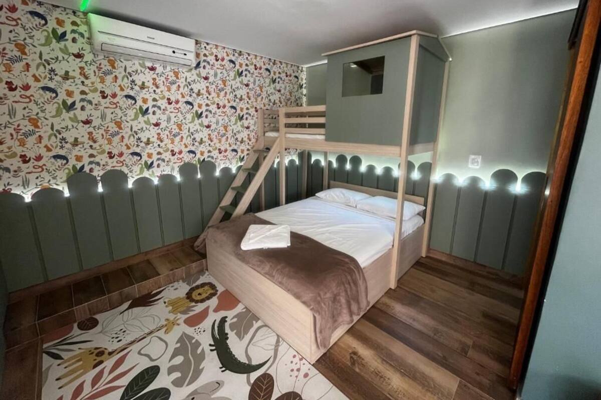 A bunk bed room with a patterned wall, a small window, and a wooden floor.