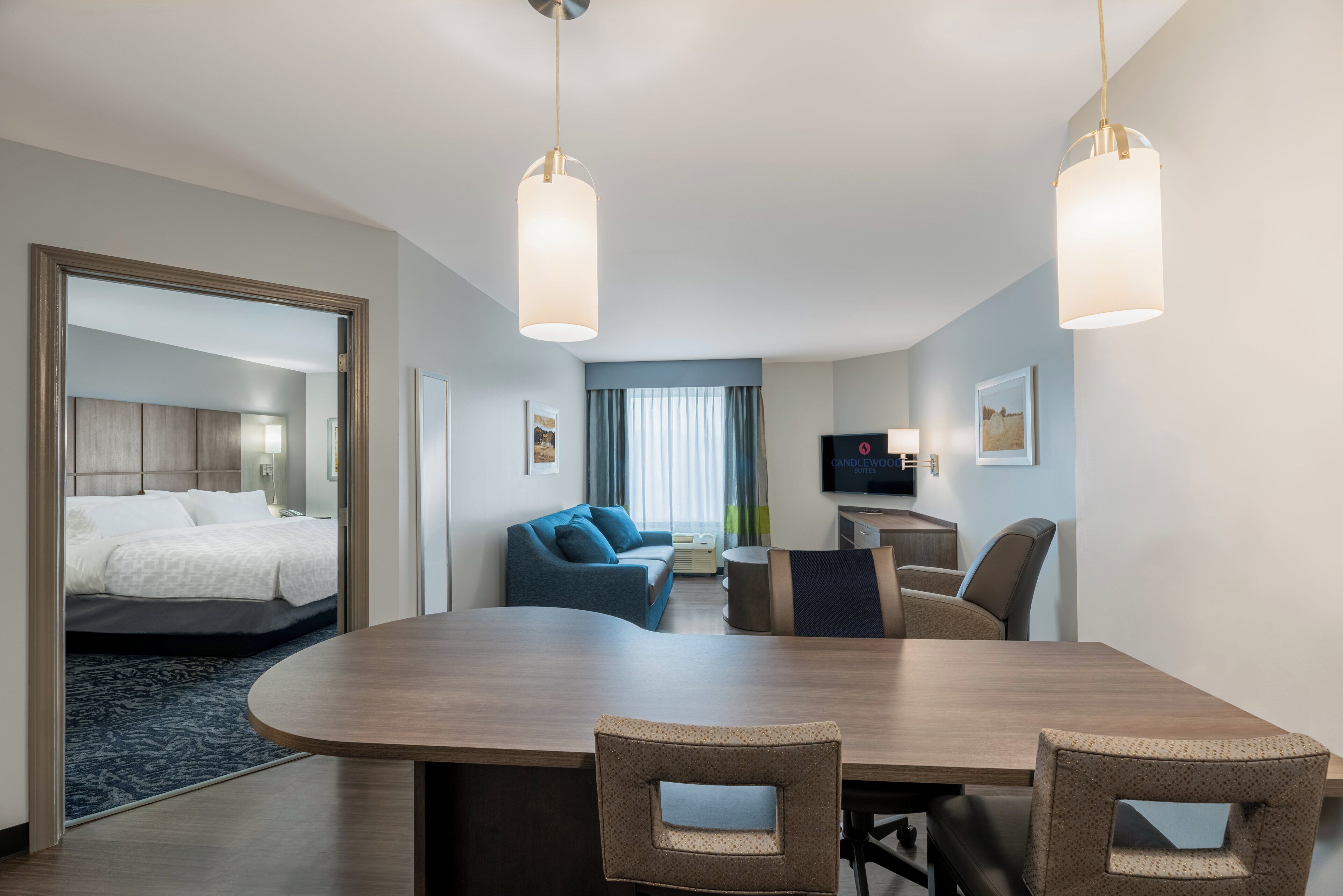 Habitación de hotel con cama, zona de estar con sofá y sillones, mesa de comedor y televisión.