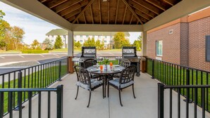 An outdoor patio with a brick wall, a covered area with a wooden ceiling, and a grill station. - Candlewood Suites Cookeville by IHG (Cookeville)