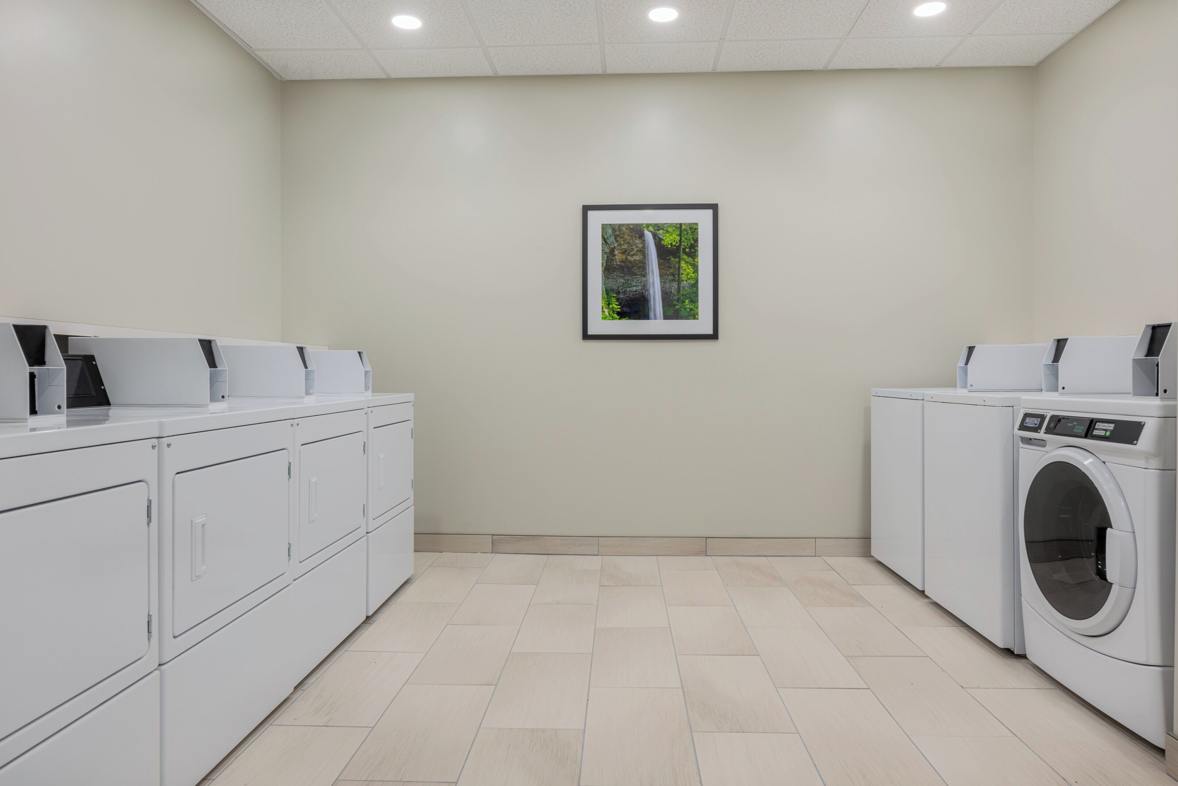 A laundry room with white cabinets, a washing machine, and a framed picture on the wall.
