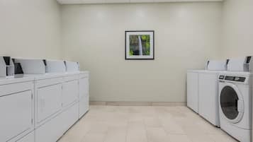 A laundry room with white cabinets, a washing machine, and a framed picture on the wall.