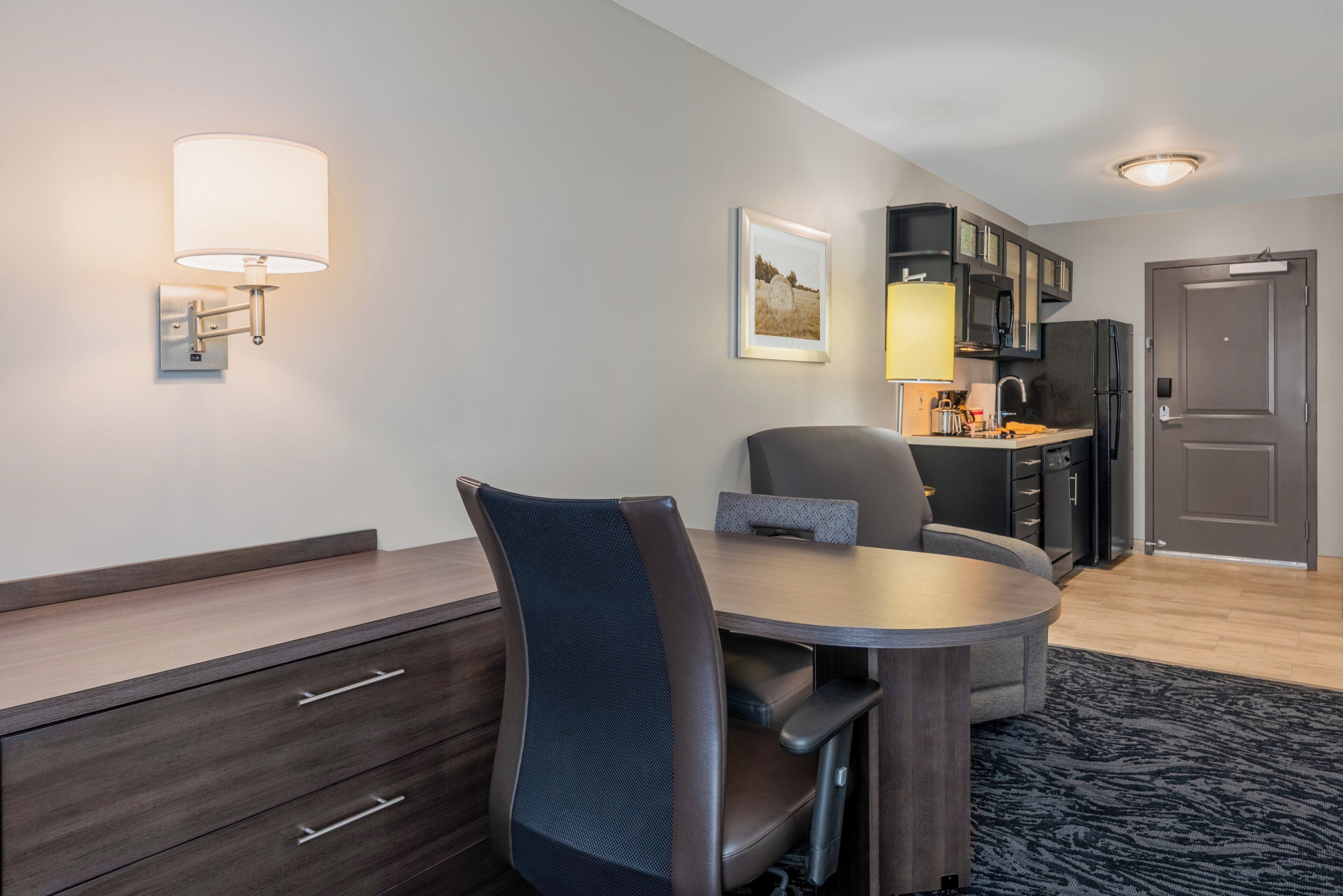 A modern kitchen with a refrigerator, stove, and microwave. There is a dining area with a table and chairs.