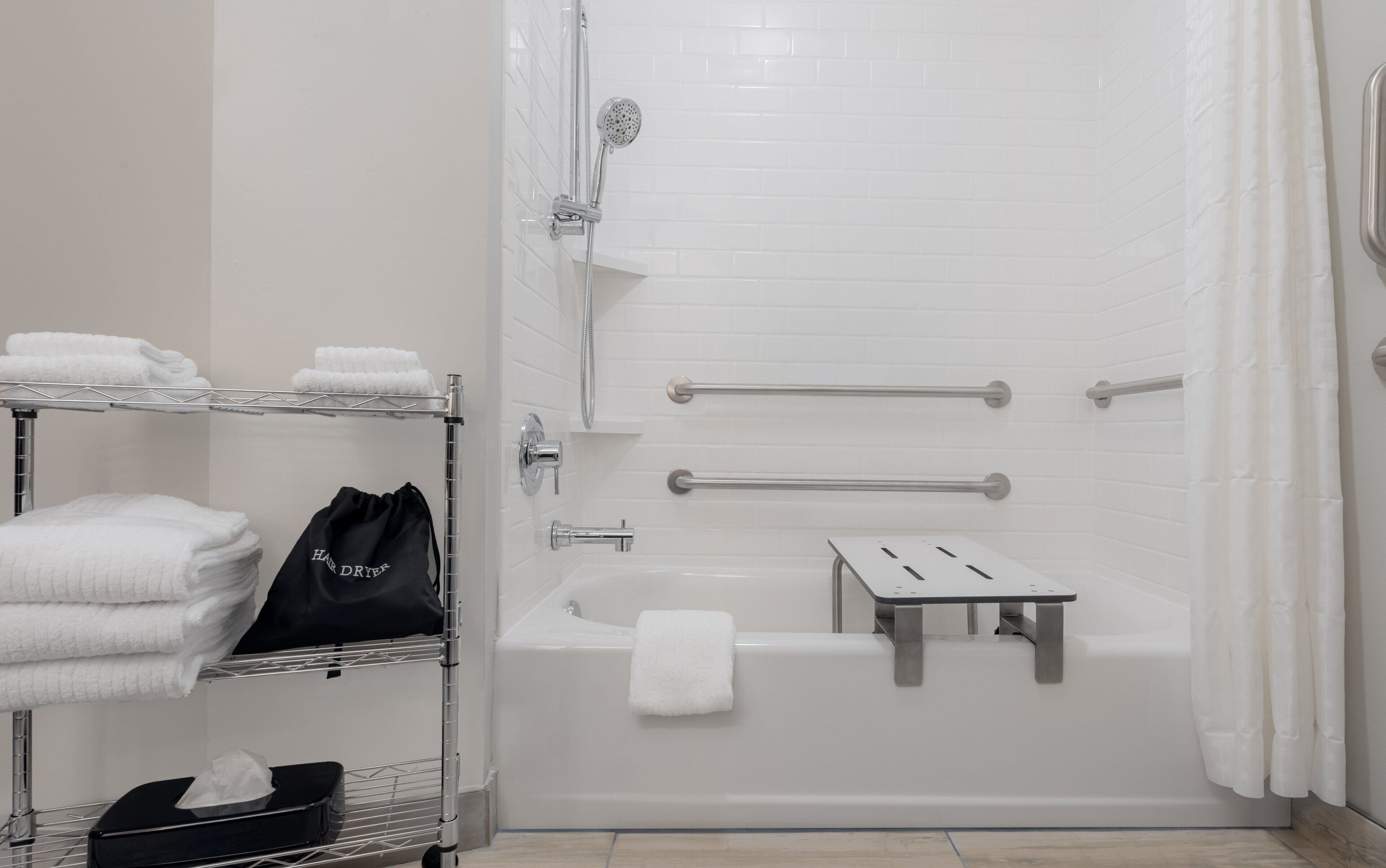 A bathroom with a bathtub, a shower, and a towel rack with towels and a hair dryer.