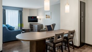 A modern hotel room with a dining area, a sofa, a TV, and a refrigerator. - Candlewood Suites Cookeville by IHG (Cookeville)