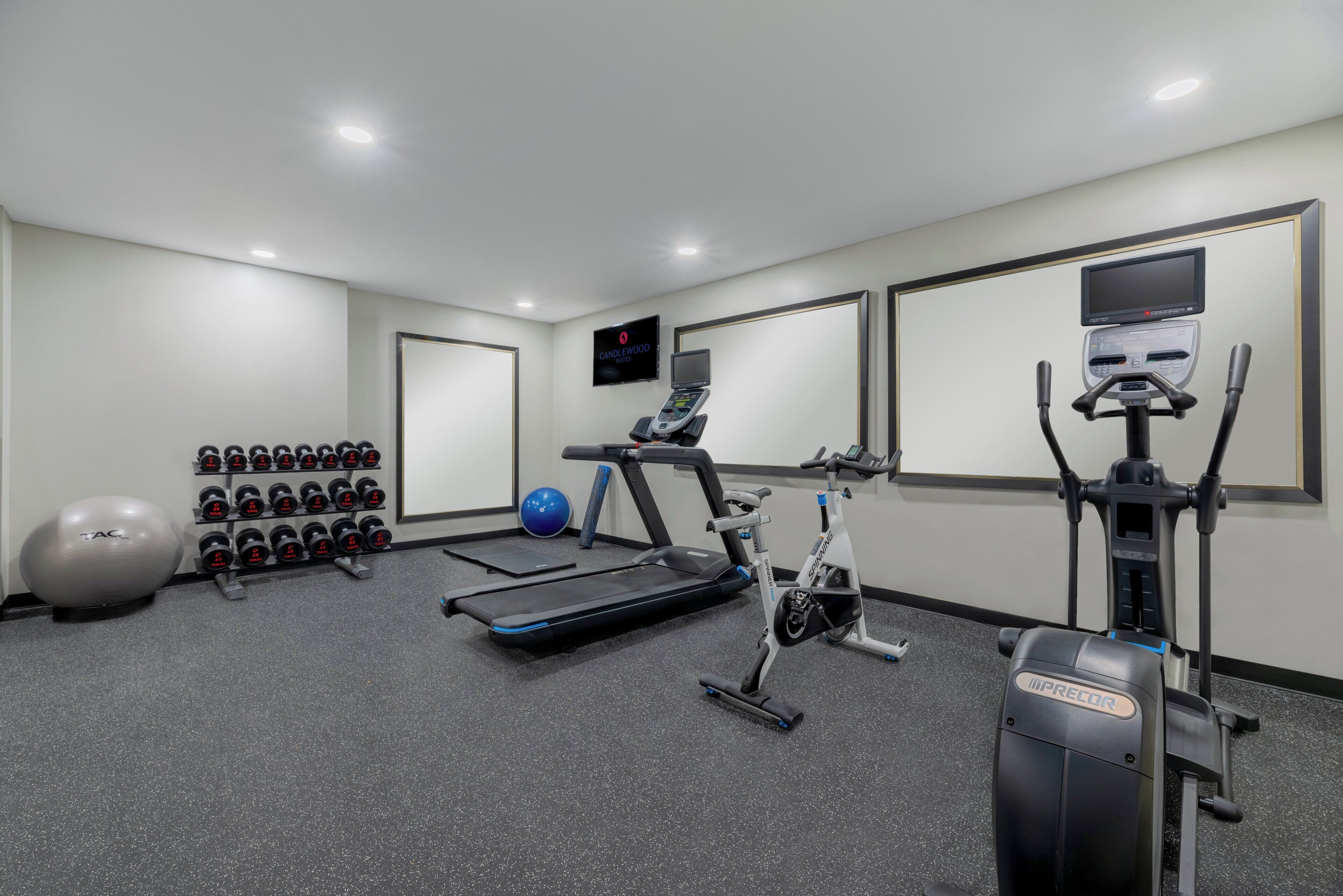 Un gimnasio con equipo de ejercicio, incluyendo una caminadora, bicicleta estática y pesas.