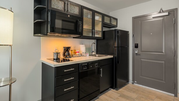 A modern kitchen with black cabinetry, a stainless steel refrigerator, and a built-in microwave. - Candlewood Suites Cookeville by IHG (Cookeville)