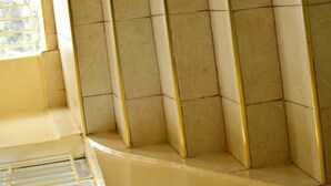 Canto de um quarto com paredes revestidas de azulejos bege e detalhes em amarelo.