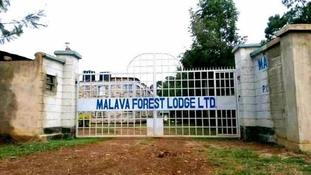 Uma entrada gradeada para Malaya Forest Lodge Ltd., com um portão de metal e uma placa.