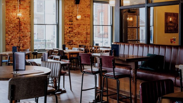 A restaurant interior with brick walls, wooden tables, and leather booths. - Westow House - London Crystal Palace (London)