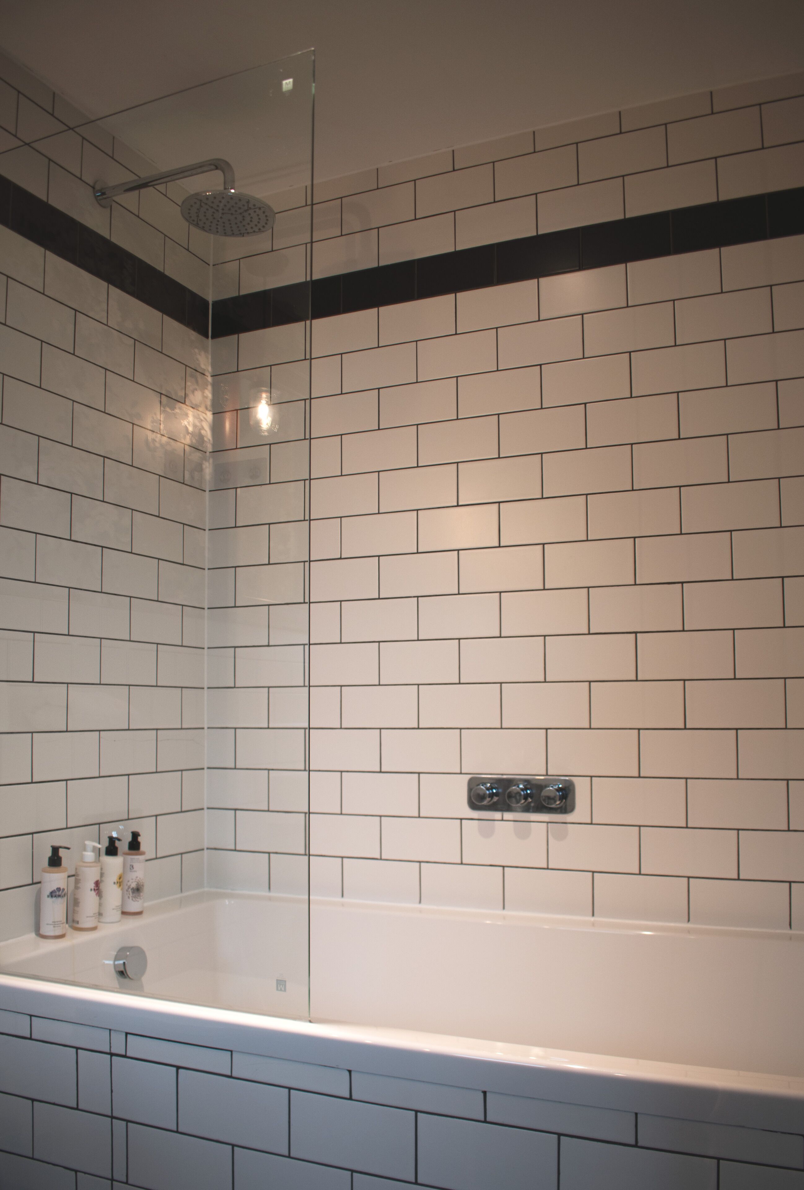 A modern bathroom with white subway tiles, a glass-enclosed shower, and a bathtub.