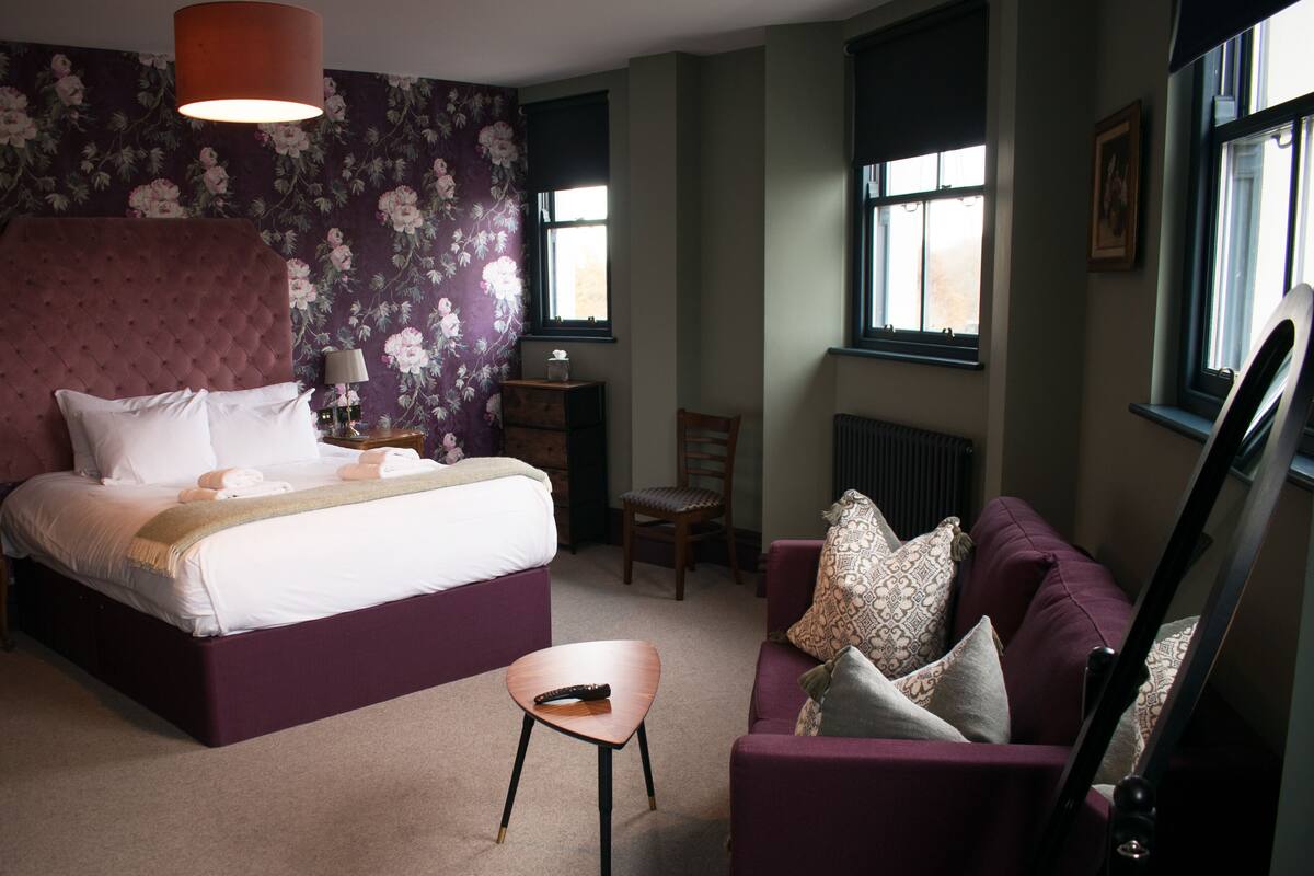 A bedroom with a large bed, a chair, a couch, and a radiator.