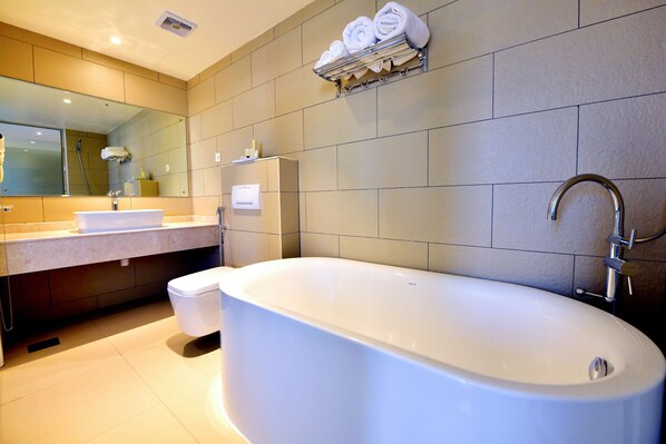A modern bathroom with a freestanding bathtub, a vanity with a mirror, and a towel rack above the sink. - Top Be Inn Hotel - Al Khoud Muscat (Seeb)