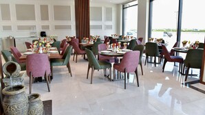 Ein modernes Restaurant mit verschiedenen Sitzmöglichkeiten, darunter Tische und Stühle, und einem großen Fenster mit Blick auf den Parkplatz.