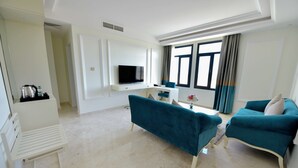 Ein modernes Wohnzimmer mit Fernseher, petrolfarbenen Sofas und einem Couchtisch.