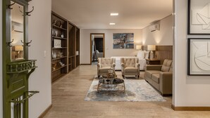 Un salón espacioso con un sofá grande, dos sillones, una mesa de centro y una estantería.