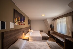 A hotel room with two beds, a large window with sheer curtains, a painting on the wall, and a small desk with a lamp. - Hotel Fioreze Centro (Gramado)