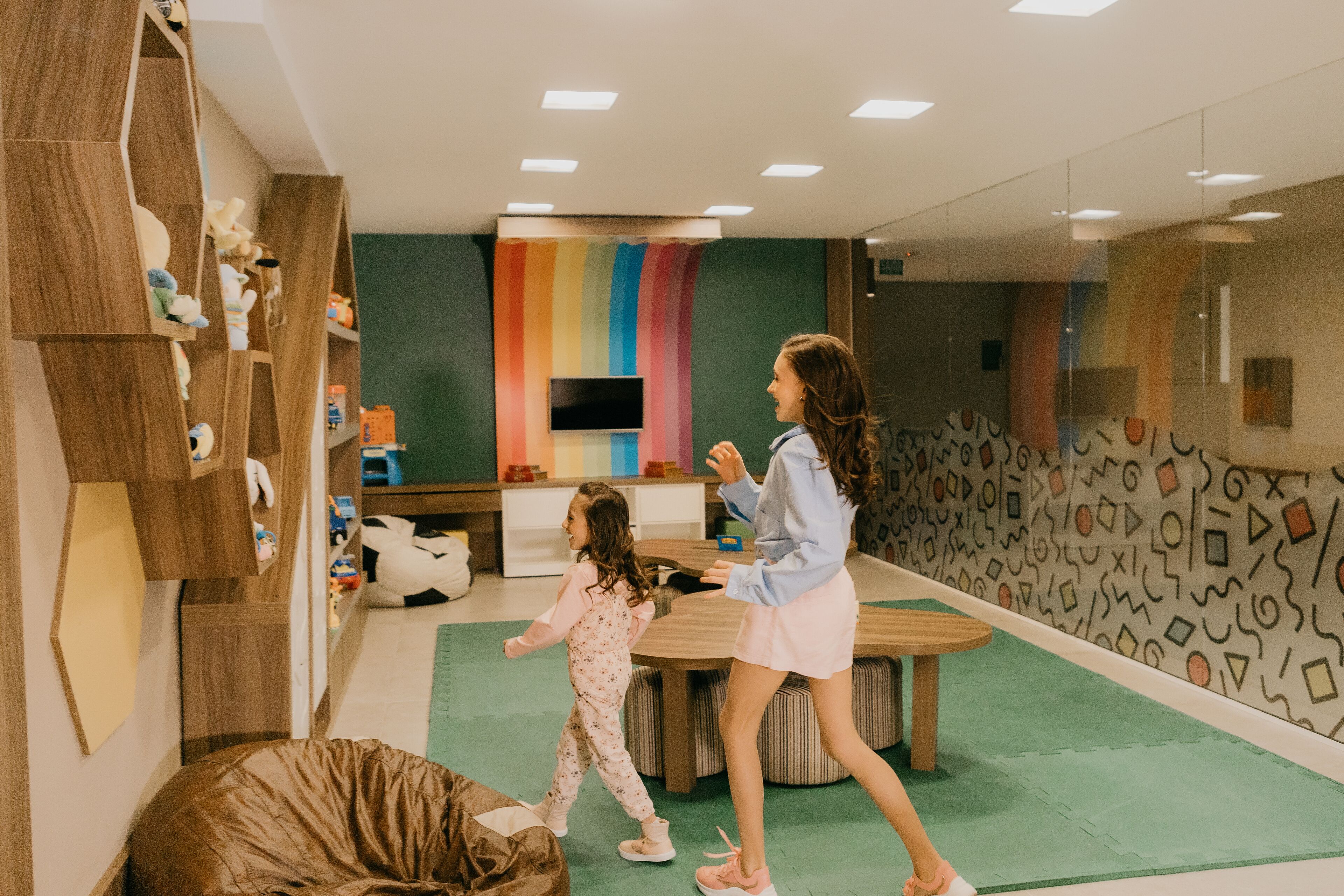 Una habitación moderna con estantería de madera, pared de color, televisor de pantalla plana y alfombra verde.