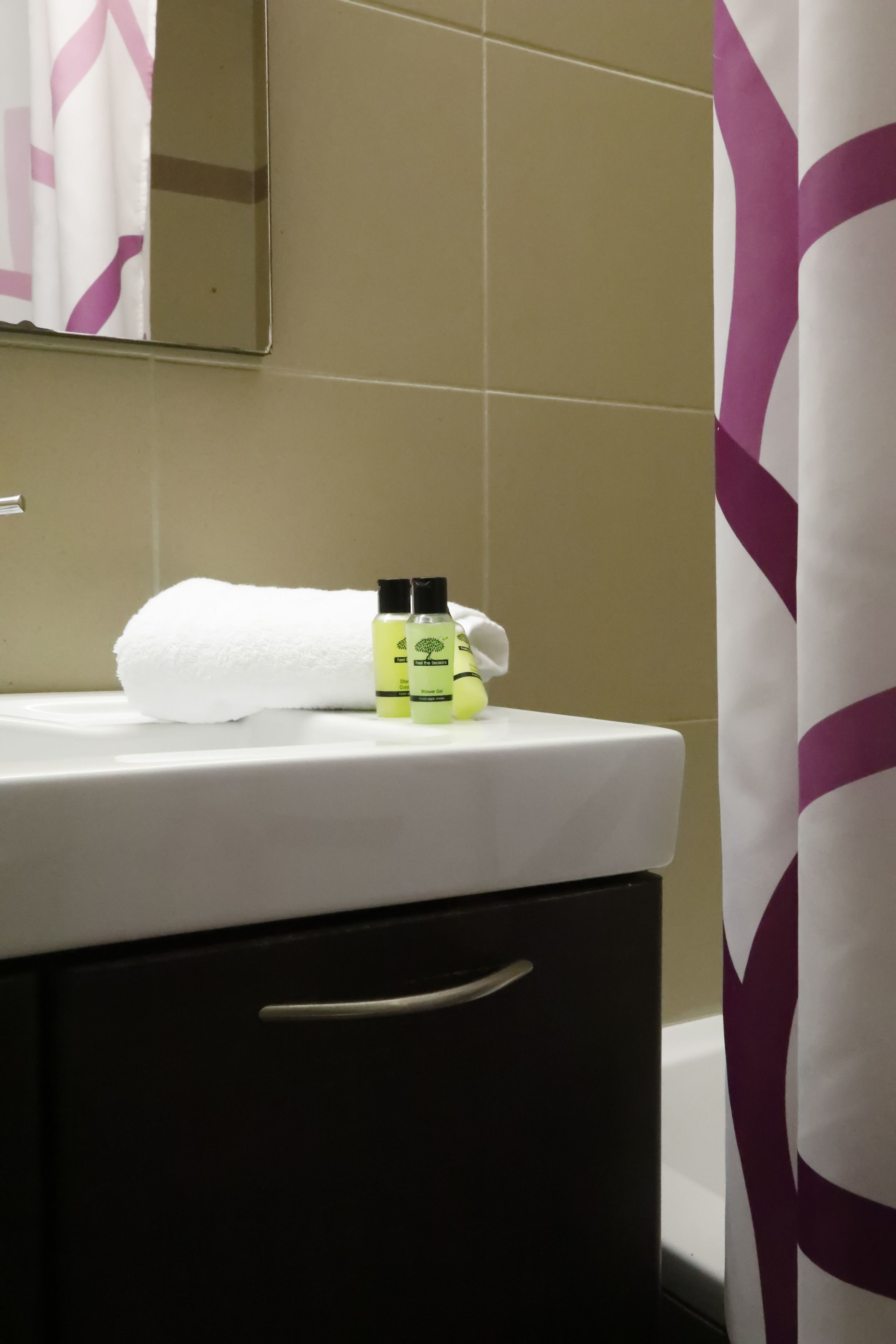 A bathroom with a white sink, a white towel, and two green bottles on the counter.