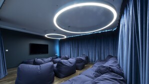 Una sala de estar moderna con un sofá seccional, un televisor de pantalla plana montado en la pared y un techo con lámparas circulares.