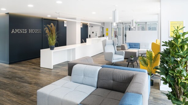 Una recepción moderna con un mostrador de recepción, zona de estar y un cartel que dice "AMNIS HOUSE".